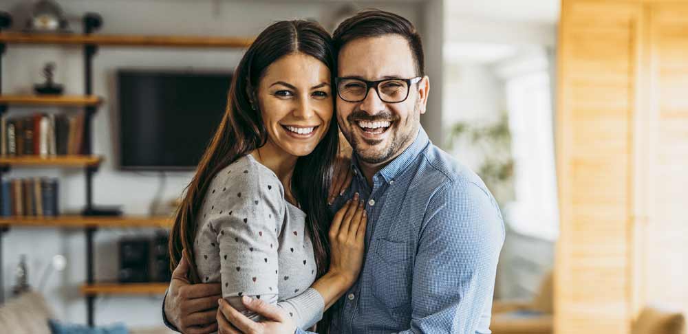 couple smiling confidently since they have great smiles because of dental implants